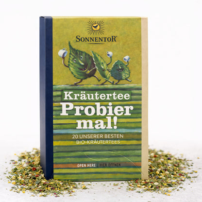 Sonnentor Probier mal! Kräutertee mit 20 besten Kräutertees und Teemischungen in einer bunten Verpackung, Teetasse im Hintergrund