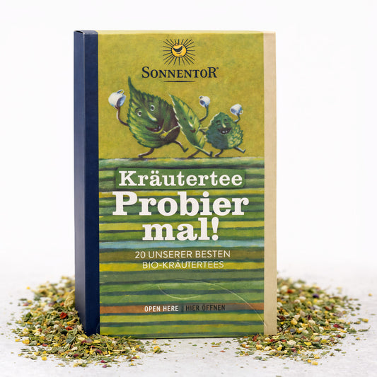 Sonnentor Probier mal! Kräutertee mit 20 besten Kräutertees und Teemischungen in einer bunten Verpackung, Teetasse im Hintergrund
