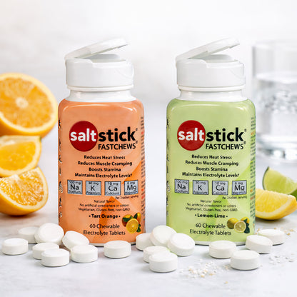 SaltStick Fast Chews Elektrolyt-Kautabletten in Orange- und Zitronen-Limetten-Geschmack, umgeben von Zitronen- und Limettenstücken sowie weißen Kautabletten auf hellem Untergrund.