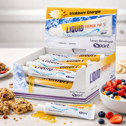 sanct bernhard sport liquid energie Tuben in offener Box, im Vordergrund eine Tube mit ausgelaufener Flüssigkeit, daneben Müsliriegel und eine Schale mit Beeren.