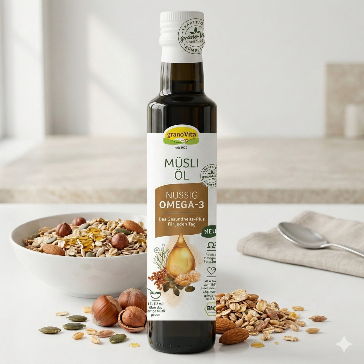 Grano Vita Müsliöl nussig vor einer Bowl mit Müsli und Nüssen, daneben Müslizutaten und ein Löffel auf hellem Tisch.