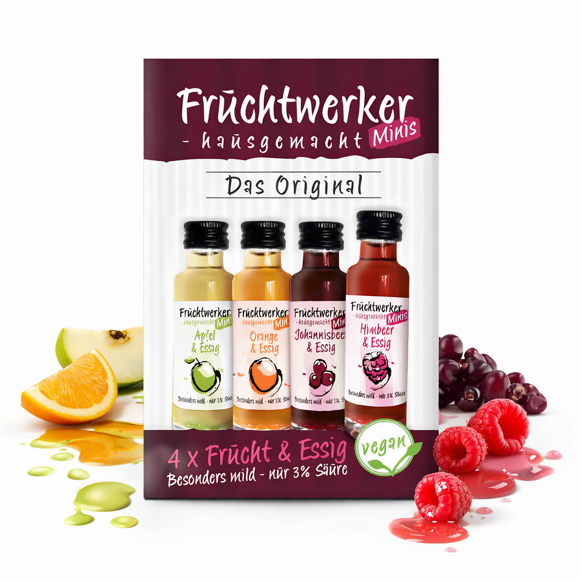 Fruchtwerker Minis 4er-Set mit Essig in den Sorten Apfel, Orange, Johannisbeere und Himbeere, Fläschchen vor Verpackung, umgeben von fruchtigen Zutaten und Spritzern.
