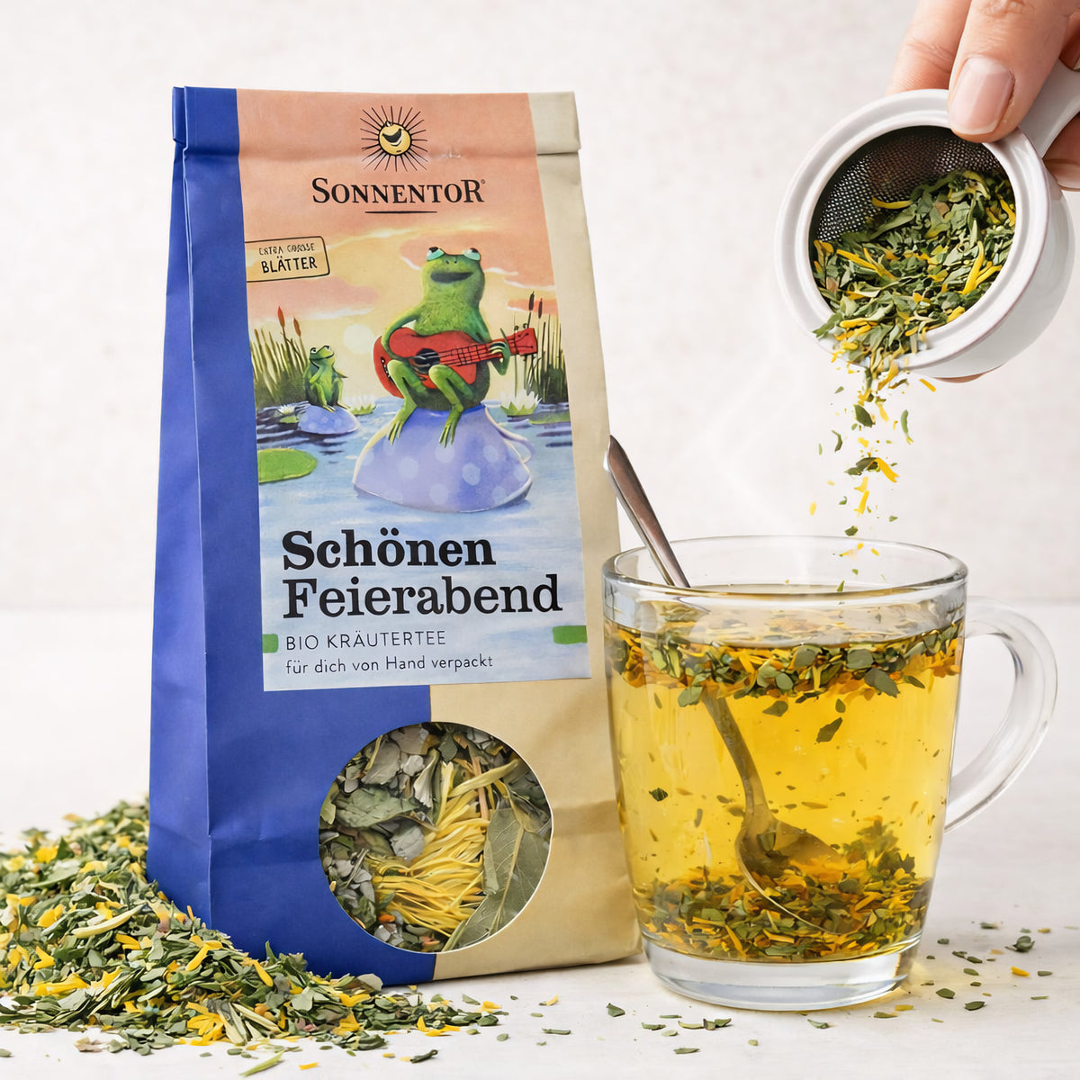 Lose Kräutertee "Schönen Feierabend" von Sonnentor in einer transparenten Teeverpackung mit frischen Kräutern.