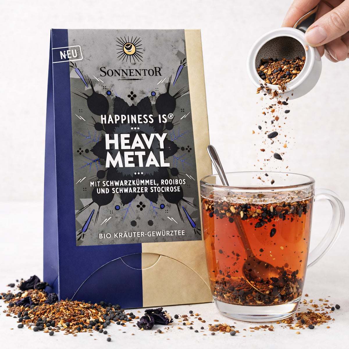 Bio-Frühstückstee von Sonnentor, "Happiness is Heavy Metal", mit Kräutern, in einer 27g Packung, auf einem rustikalen Holztisch.