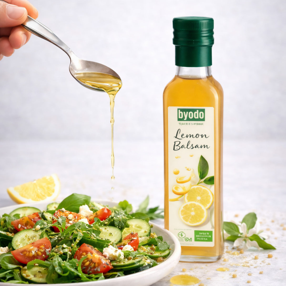 byodo lemon balsam essig neben einem frischen Salat, ein Löffel mit balsam wird darüber gehalten.