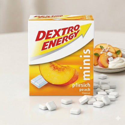 Dextro Energy mini pfirsich geschmack Packung mit verstreuten Traubenzucker-Tabletten, im Hintergrund ein Teller mit Joghurt und Pfirsichspalten.