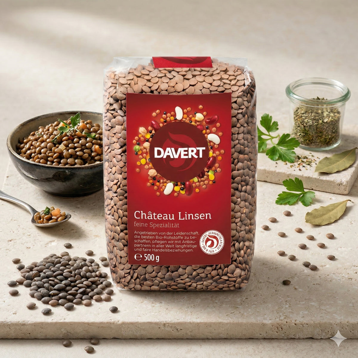 Davert braune Tellerlinsen 500g auf Steinplatte, daneben gekochte linsen im Schälchen, Kräuter, Lorbeerblatt und Gewürzglas.