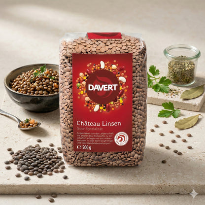 Davert braune Tellerlinsen 500g auf Steinplatte, daneben gekochte linsen im Schälchen, Kräuter, Lorbeerblatt und Gewürzglas.