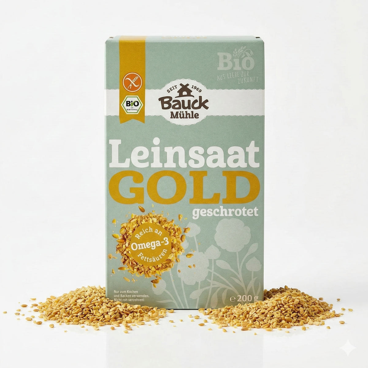 Packung Bauckhof Bio Gold-Leinsaat geschrotet glutenfrei 200g stehend, umgeben von verstreuter geschroteter Leinsaat auf weißem Hintergrund.