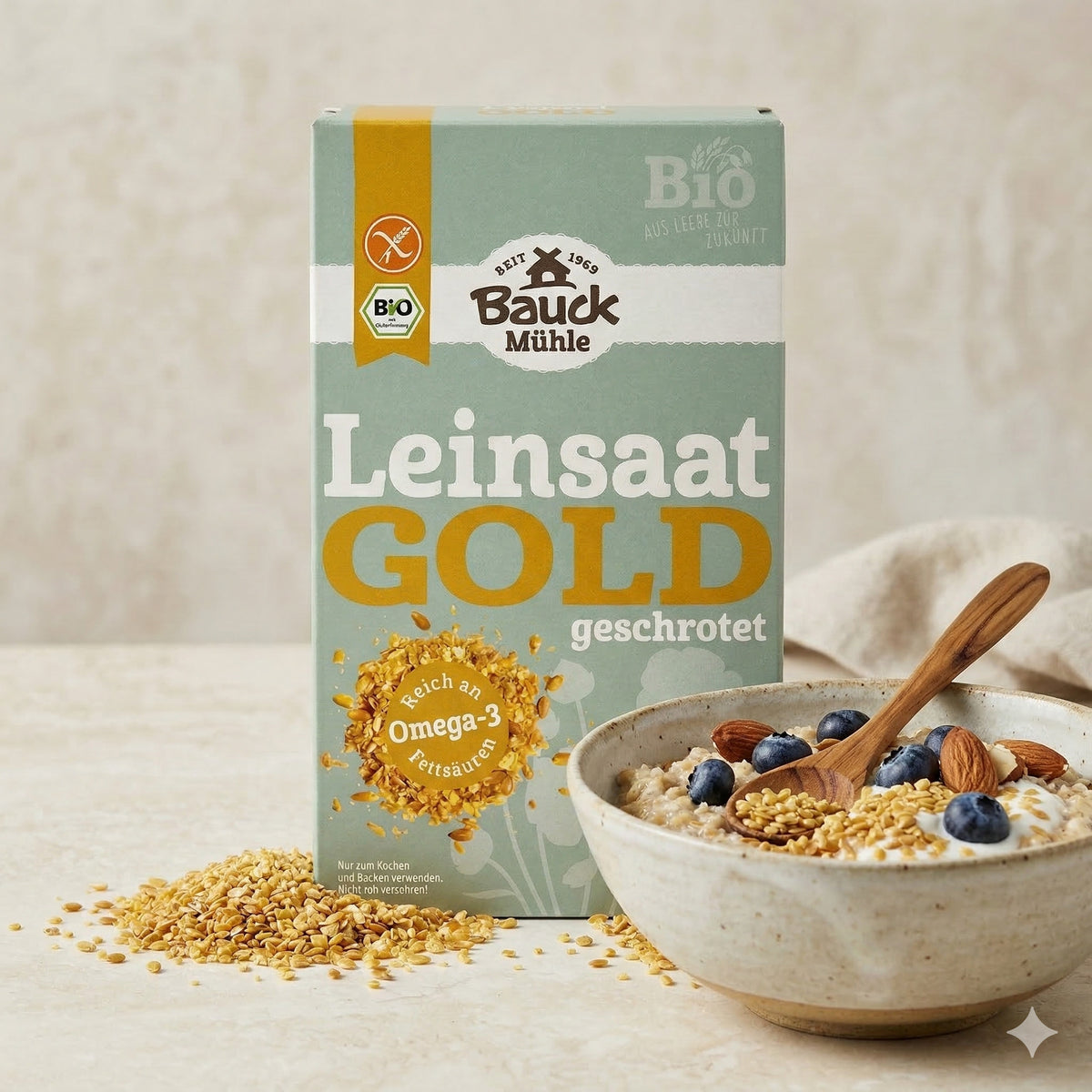 Bauckhof Gold-Leinsaat geschrotet glutenfrei 200g neben einer Schale Porridge mit Blaubeeren, Mandeln und Leinsaat, Löffel in der Schale.