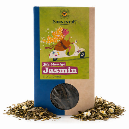 Packung Sonnentor blumige Jasmin Tee lose 100g mit Sichtfenster, umgeben von losem grünen Tee und Jasminblüten auf weißem Hintergrund.