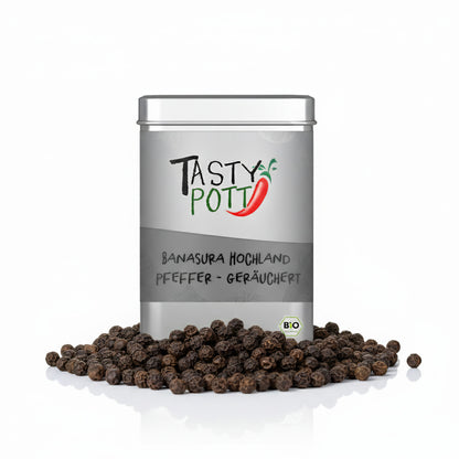 Tasty Pott Banasura Pfeffer Dose, umgeben von ganzen schwarzen Pfefferkörnern auf weißem Hintergrund.