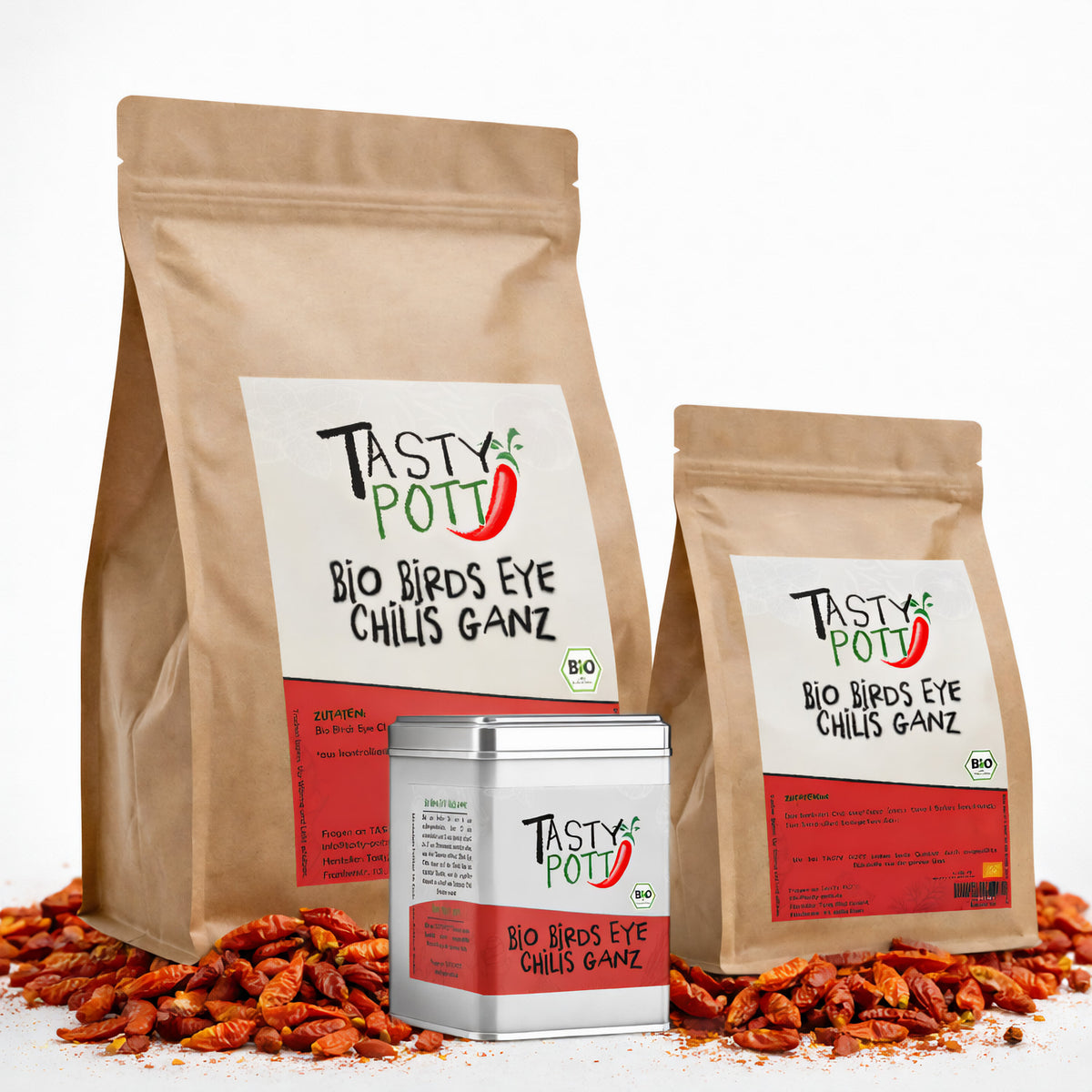 Drei Tasty Pott Nachfüllbeutel und eine Dose Bio Birds Eye Chilis ganz, getrocknet, auf einem Bett aus getrockneten Chilis stehend.