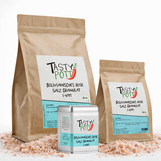 Drei Tasty Pott Nachfüllbeutel und eine Dose bolivianisches Rosé Salz Granulat auf rosa Salz liegend, Vorderseiten mit Etiketten sichtbar.