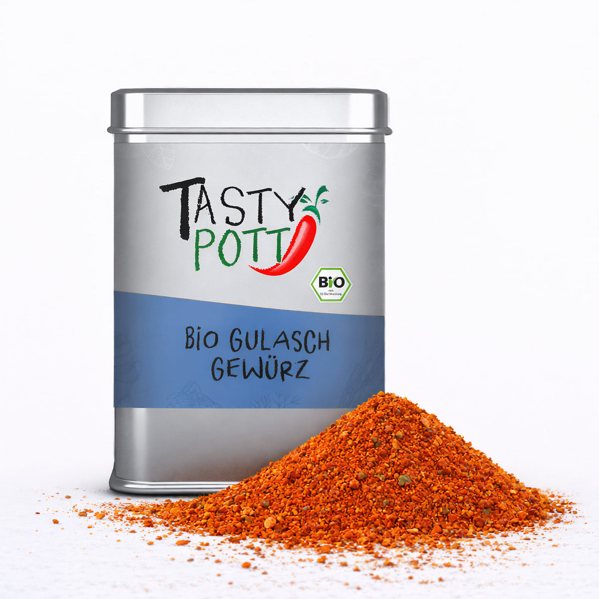 Tasty Pott Bio Gulaschgewürz in silberner Dose mit blauem Etikett, davor ein Haufen der roten Gewürzmischung auf weißem Untergrund.