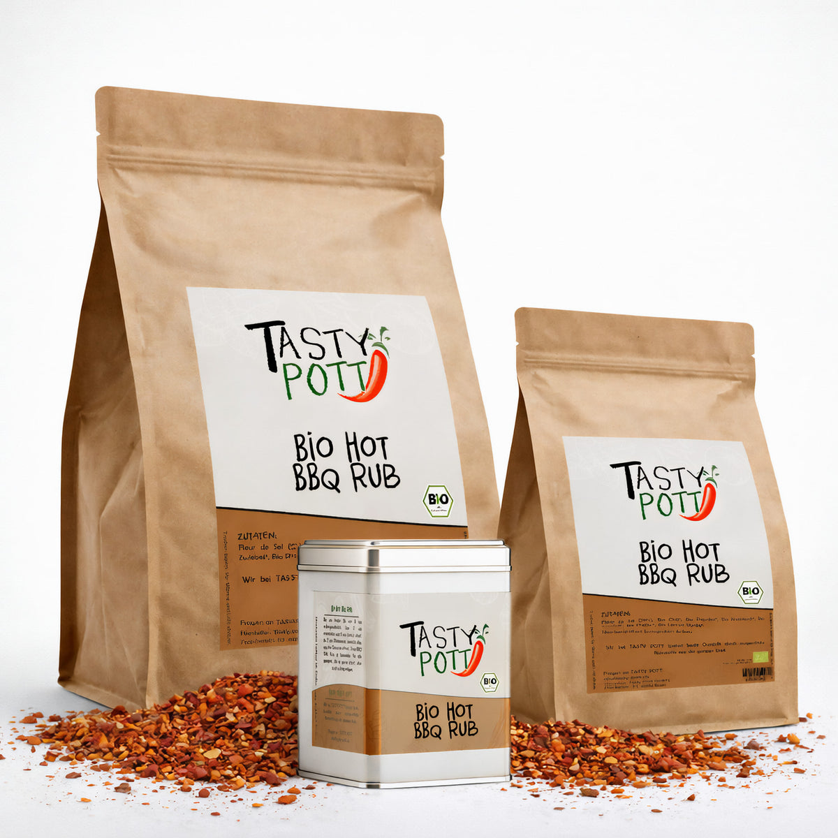 Drei Tasty Pott Bio Hot BBQ Rub Nachfüllbeutel und eine Dose stehen auf einer Fläche mit verstreuten scharfen Grillgewürzen.