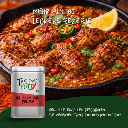 Tasty Pott Bio India Chili Pulver Dose vor einer Pfanne mit indischem Currygericht, dekoriert mit Chili und Zitrone.