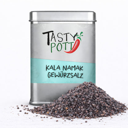 Tasty Pott Kala Namak Salz in silberner Dose mit türkisfarbenem Etikett, davor ein Haufen grobkörniges indisches Schwarzsalz auf weißem Untergrund.