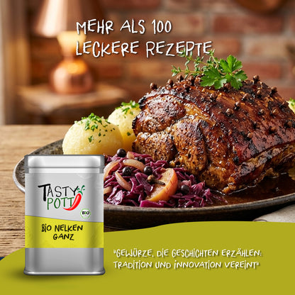 Tasty Pott Bio Nelken ganz Dose vor Teller mit Braten, Rotkohl und Klößen, dekoriert mit Nelken, im rustikalen Ambiente.