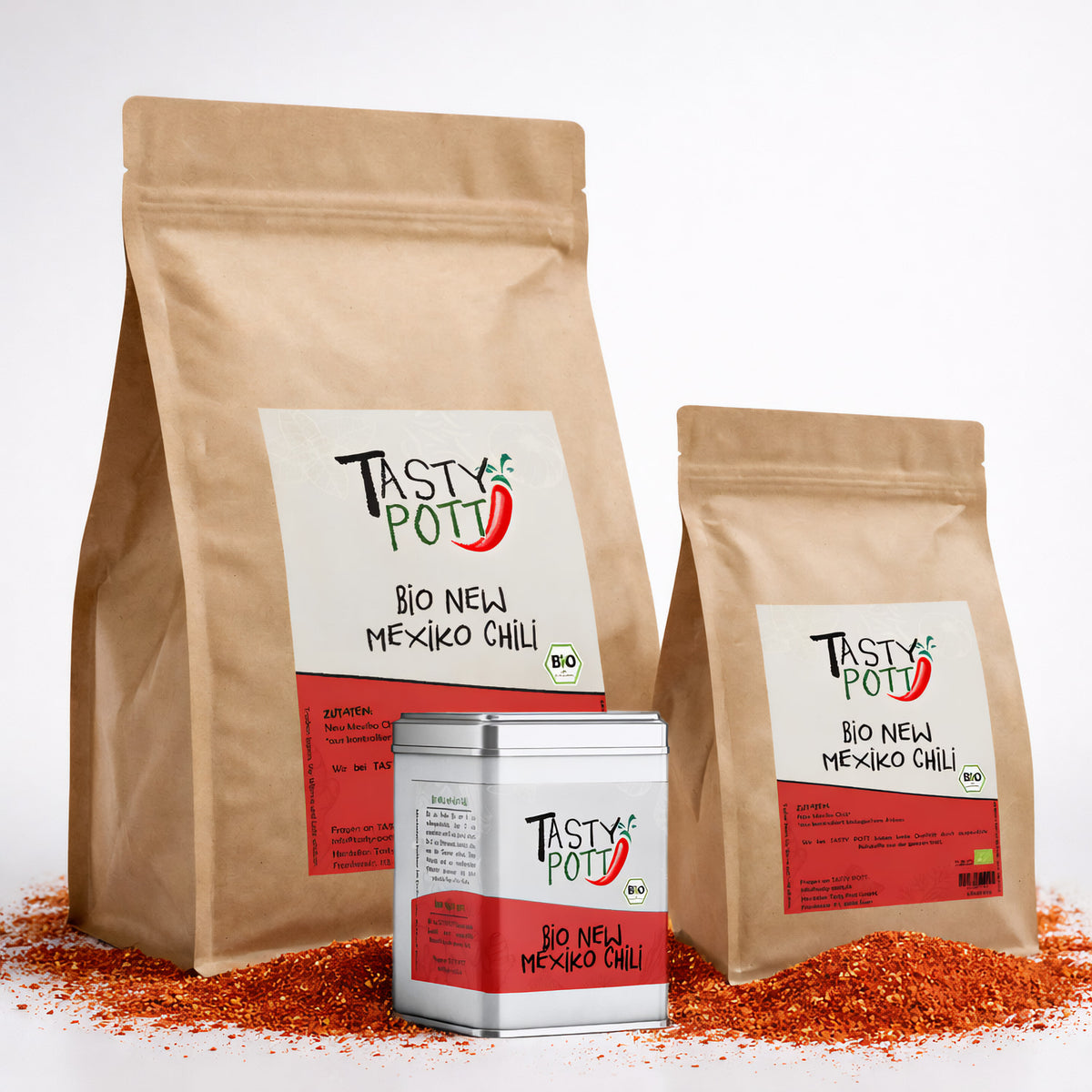 Drei Tasty Pott Bio New Mexiko Chili Nachfüllbeutel und eine Dose stehen auf verstreutem Chili Pulver, alle mit sichtbarem Etikett.