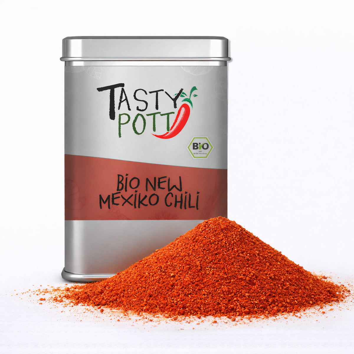 Tasty Pott Bio Mexiko Chili Pulver in silberner Dose mit rotem Etikett, davor ein Haufen leuchtend rotes Chili Pulver auf weißem Untergrund.