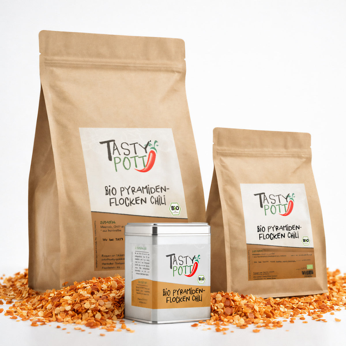 Drei Tasty Pott Beutel und eine Dose Bio Pyramidenflocken Chili Salz auf einem Haufen Chili-Salz-Flocken stehend.