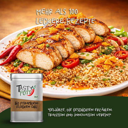 Tasty Pott Bio Pyramidenflocken Chili Salz Dose vor einem Teller mit gewürztem Fleisch, Bulgur und Chili auf einem gedeckten Tisch.