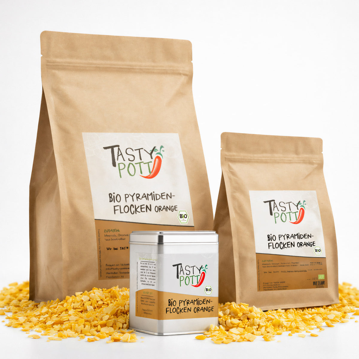 Drei Tasty Pott Nachfüllbeutel und eine Dose Bio Pyramidenflocken Orange auf verstreuten orangenen Salzflocken, Vorderseiten mit Etikett sichtbar.