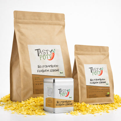 Drei Tasty Pott Nachfüllbeutel und eine Dose Bio Pyramidenflocken Zitrone stehen auf gelben Zitronensalzflocken.