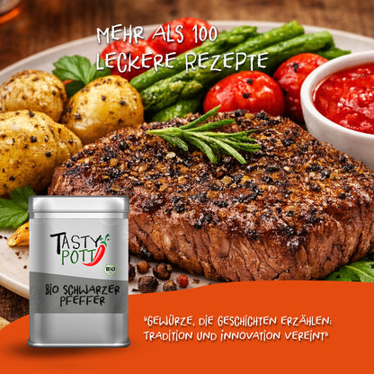 Tasty Pott Dose Bio schwarzer Pfeffer ganz vor einem angerichteten Steak mit Gemüse und Kartoffeln auf einem Teller.