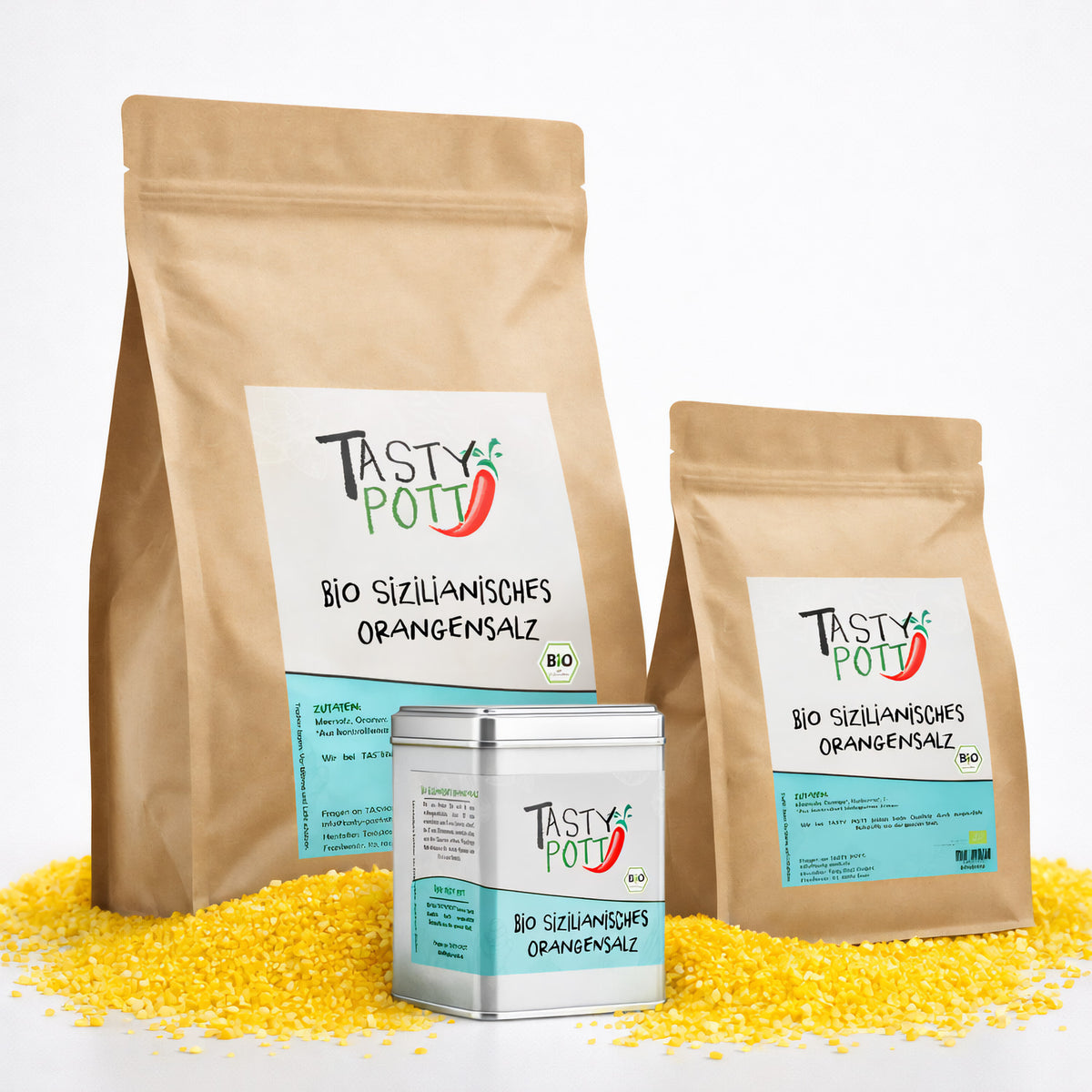 Drei Verpackungen Tasty Pott sizilianisches Bio Orangensalz, zwei braune Nachfüllbeutel und eine silberne Dose, stehend auf gelbem Orangensalz.