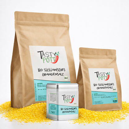Drei Verpackungen Tasty Pott sizilianisches Bio Orangensalz, zwei braune Nachfüllbeutel und eine silberne Dose, stehend auf gelbem Orangensalz.