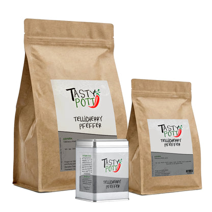 Tasty Pott Tellicherry Pfeffer schwarz, ganze Körner im braunen Beutel und silberner Dose, freigestellt auf weißem Hintergrund.