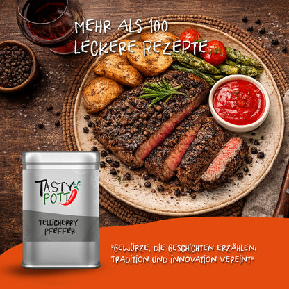 Tasty Pott Tellicherry Pfeffer schwarz, ganze Körner in silberner Dose vor einem Teller mit Steak, Kartoffeln und Gemüse.