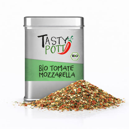 Tasty Pott Bio Tomate Mozzarella Würze in silberner Dose mit grünem Etikett, davor ein Haufen bunter Bio Kräutermischung.