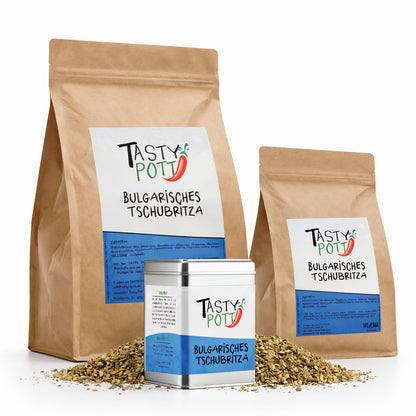 Drei Verpackungen der Tasty Pott bulgarisches Tschubritza Gewürzmischung, zwei braune Nachfüllbeutel und eine silberne Dose, davor lose Gewürze auf weißem Hintergrund.