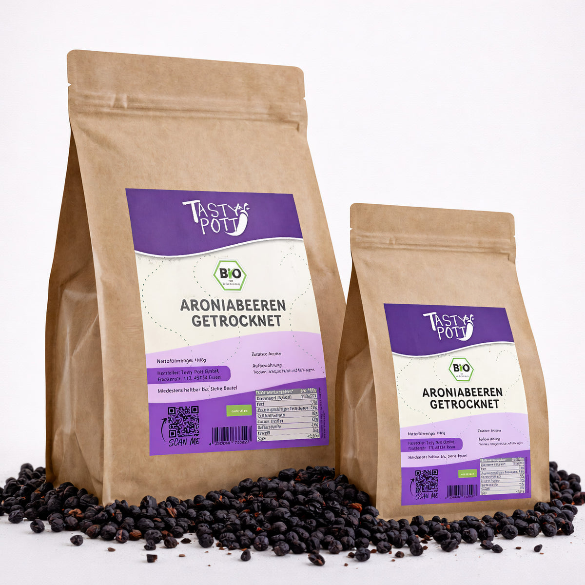 Zwei Beutel Tasty Pott Bio Aroniabeeren getrocknet stehen auf einer Unterlage aus getrockneten Beeren, Vorderseiten mit Etikett sichtbar.