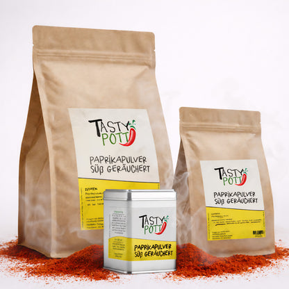Drei Tasty Pott Nachfüllbeutel und eine Dose Paprikapulver geräuchert auf Paprikapulver liegend, Vorderseiten mit Etikett sichtbar.