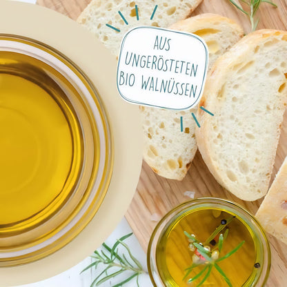 Schale mit borchers Walnussöl und Glas mit Öl neben Brotscheiben, Hinweis auf ungerösteten Bio Walnüssen.