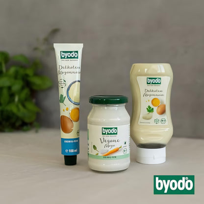 Drei Byodo Mayonnaise Produkte, darunter eine Tube Delikatess Mayonnaise, ein Glas vegane Mayo und eine Squeeze-Flasche, nebeneinander aufgestellt
