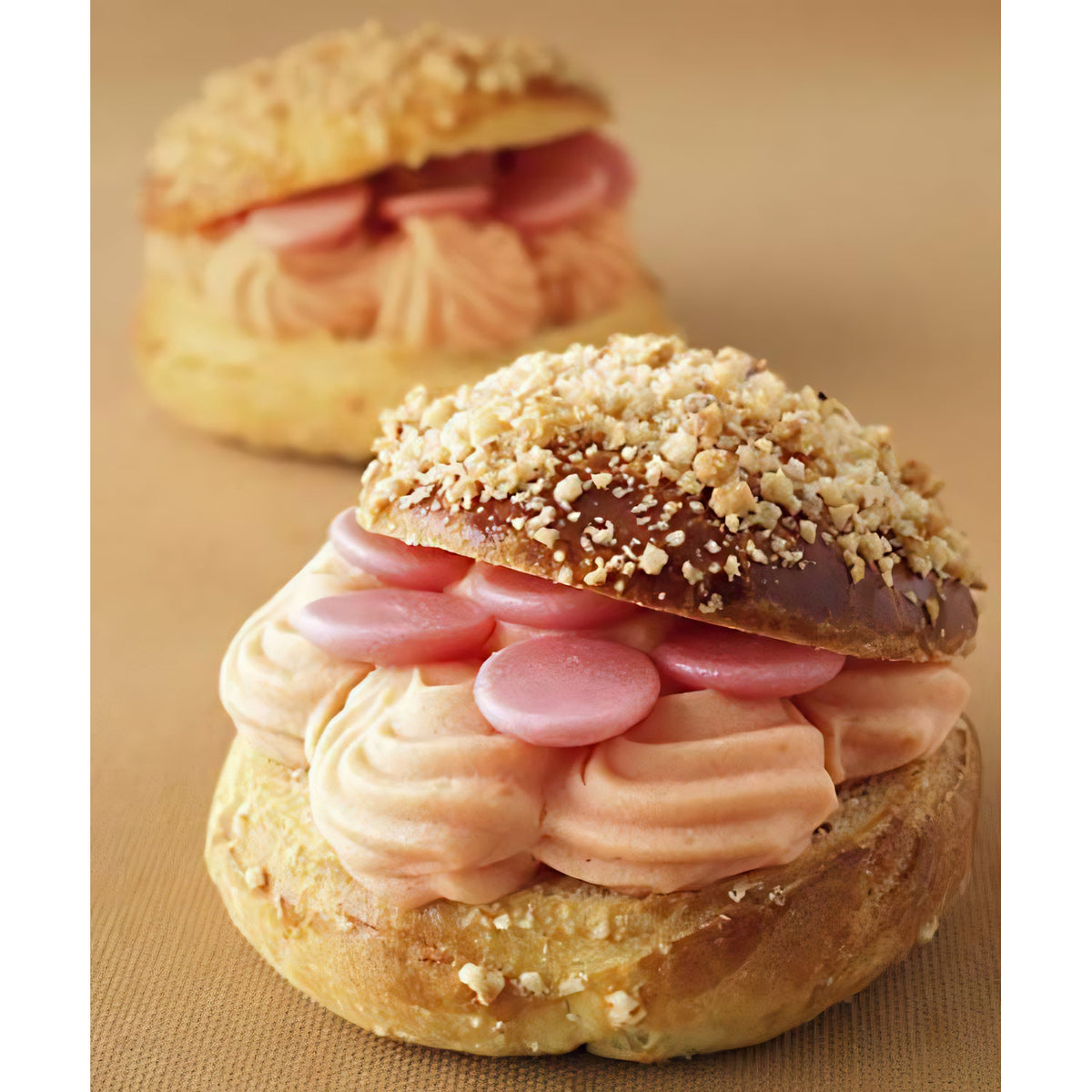 Brandteiggebäck mit Cremefüllung, dekoriert mit Callebaut strawberry flavoured chocolate drops als Dessertdekoration.
