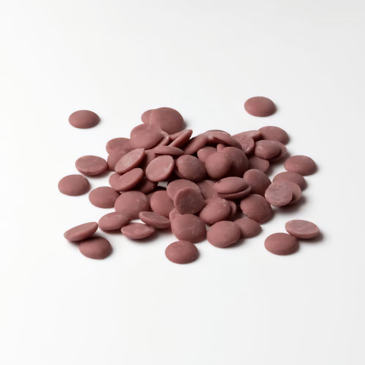 Ruby Schokolade Callets von Callebaut lose auf weißem Untergrund ausgebreitet.