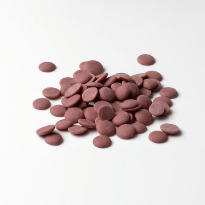 Ruby Schokolade Callets von Callebaut lose auf weißem Untergrund ausgebreitet.