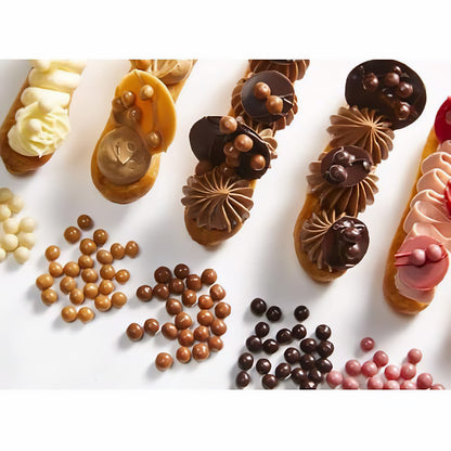 Verschiedene Eclairs mit Schokoladen-Dekor und Crispearls Salted Caramel von Callebaut als Dessertdekoration auf weißem Hintergrund.