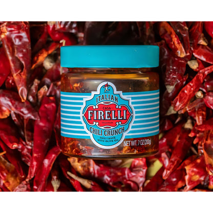Casa Firelli Chili Crunch 200g Glas auf einem Bett aus getrockneten roten Chilis.