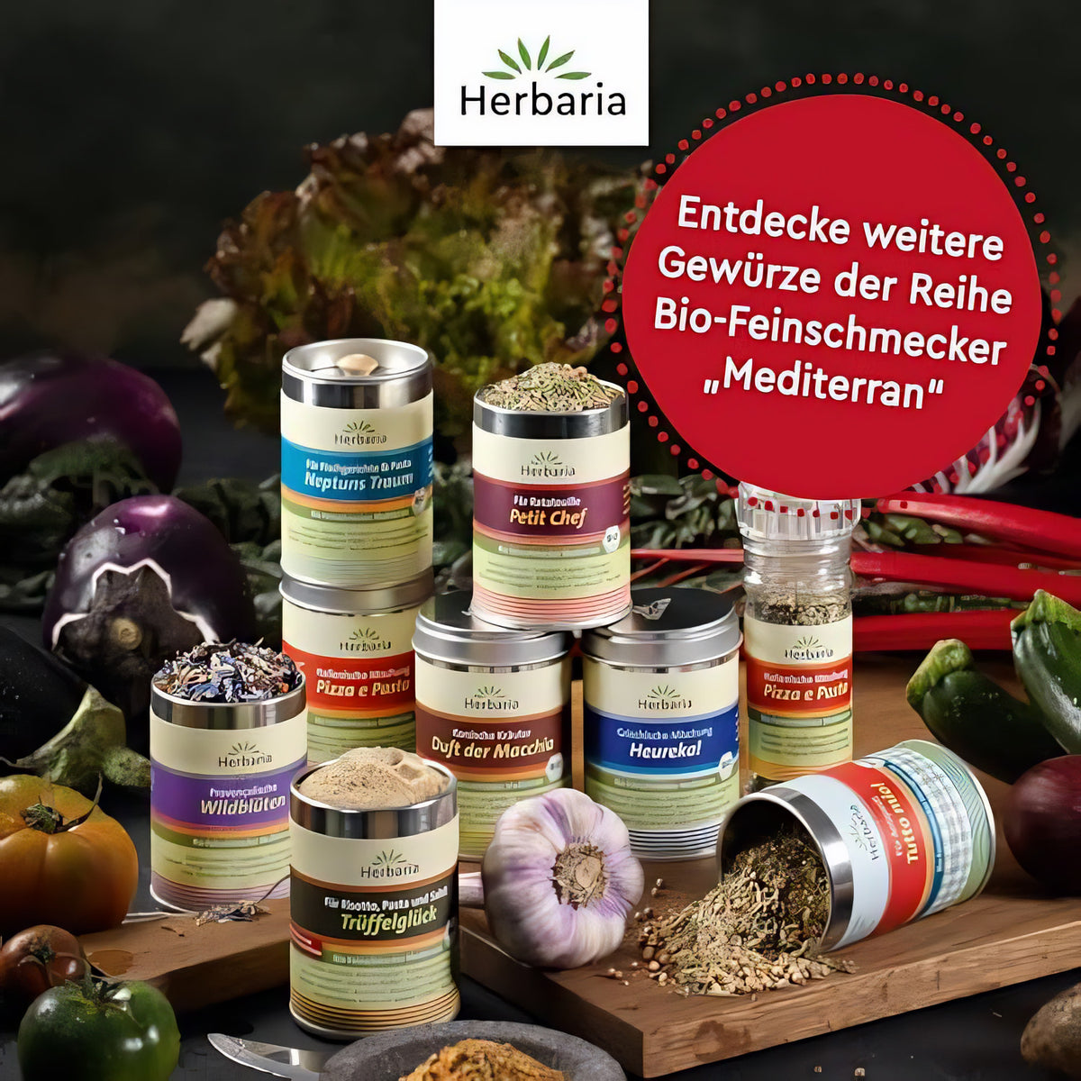 Verschiedene Herbaria Bio-Gewürzmischungen der mediterranen Reihe, darunter Tutto mio! in Mühle und Dose, arrangiert mit Gemüse auf einem Holztisch.