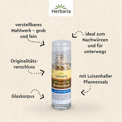 Herbaria Bauern Brotzeitsalz Mini-Mühle auf hellem Hintergrund, umgeben von erklärenden Texten zu Mahlwerk, Glaskorpus und Salz.
