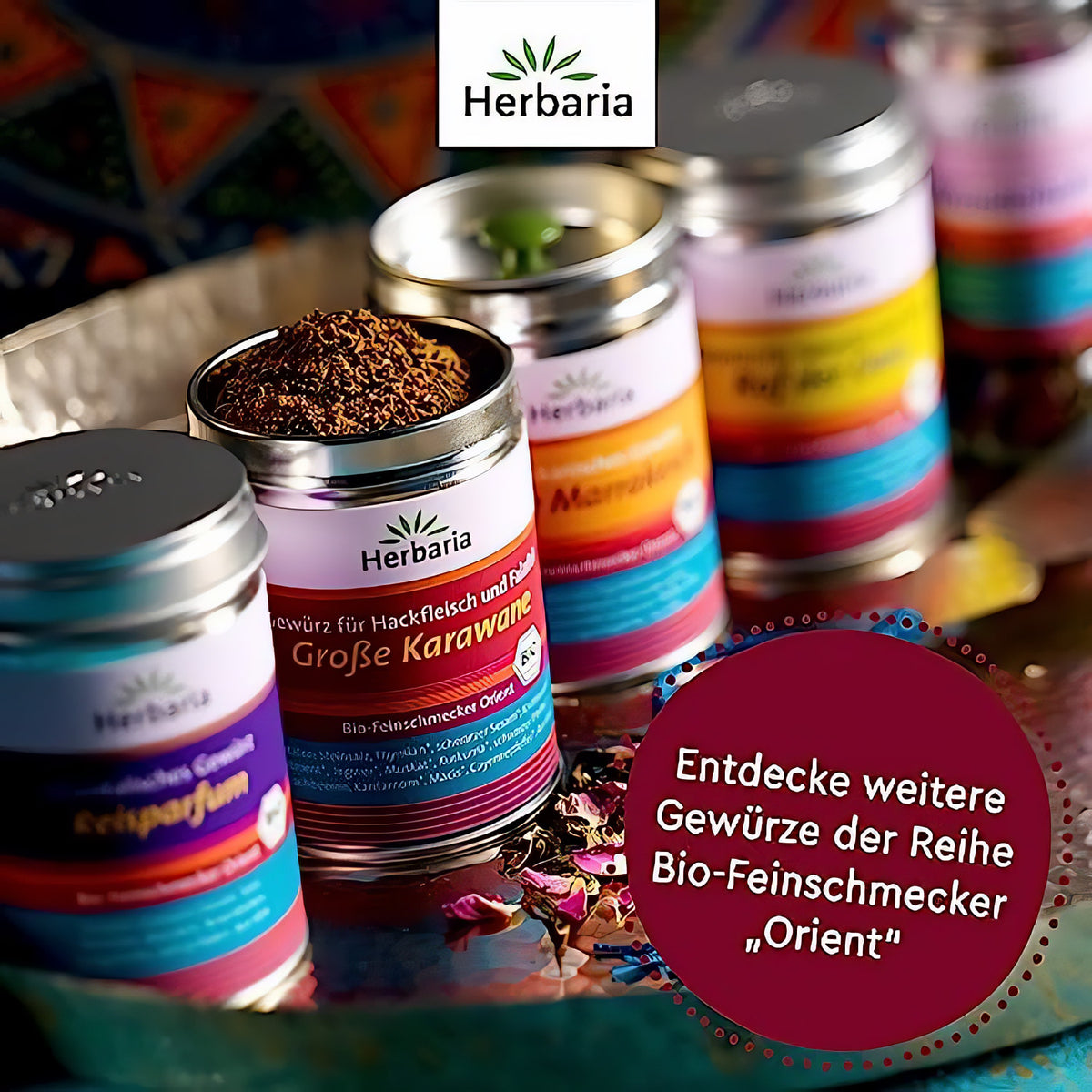 Offene Herbaria Große Karawane Dose mit Gewürzen, daneben weitere bunte Dosen der Orient-Gewürzreihe auf dekorativem Untergrund.