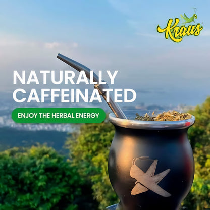Gefüllter Mate-Becher mit Metallstrohhalm und Kraus Logo, im Hintergrund Natur und Ausblick auf eine Stadt, Fokus auf den Tee im Becher.