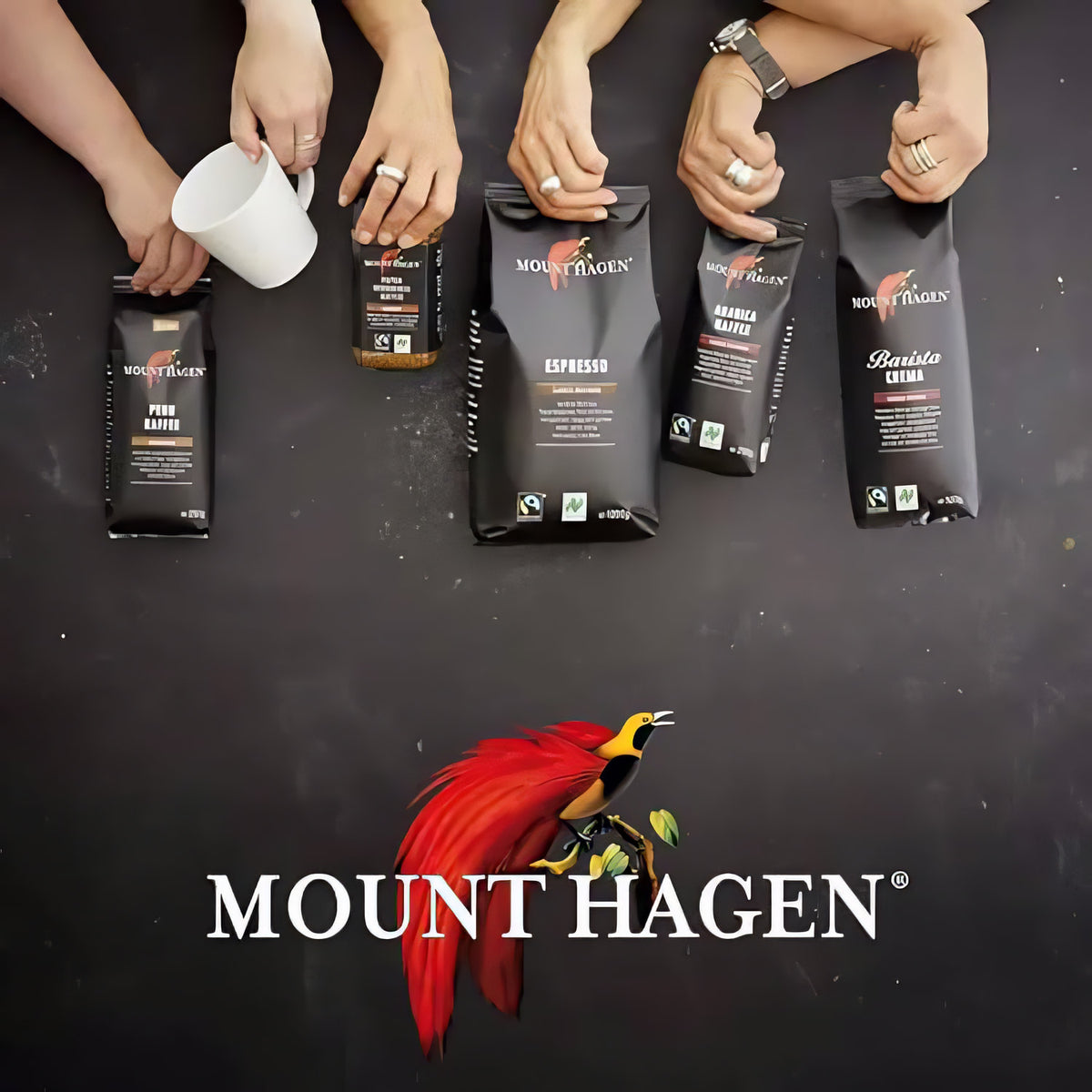 Verschiedene Mount Hagen Kaffeeprodukte, darunter Arabica Crema ganze Bohne, werden von mehreren Händen gehalten.